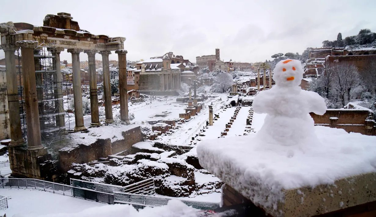 Manusia salju terlihat di dekat bangunan kuno di Roma, Italia (26/2). Badai salju yang melanda Italia menganggu transportasi dan sekolah diliburkan. (AFP Photo/Vicenzo Pinto)