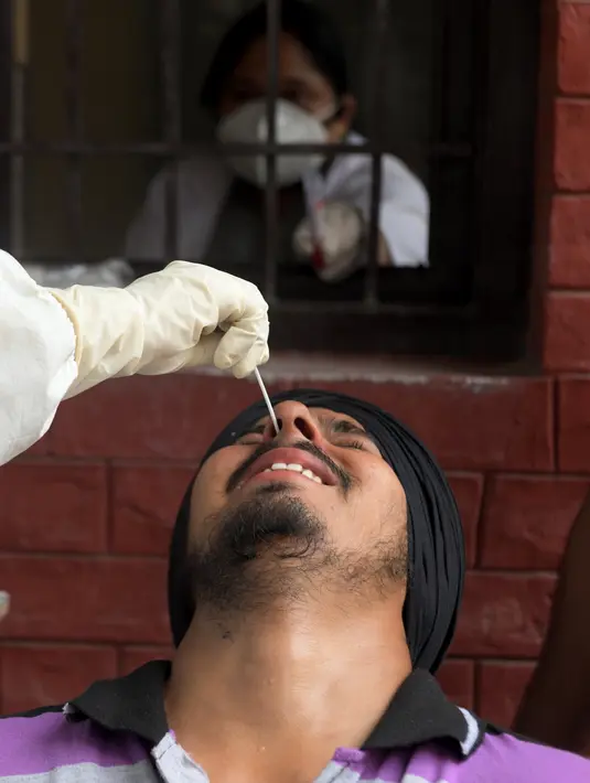 Petugas kesehatan mengambil sampel swab seorang pria untuk menguji virus corona Covid-19 di sebuah rumah sakit di Amritsar (2/9/2020). (AFP/Narinder Nanu)