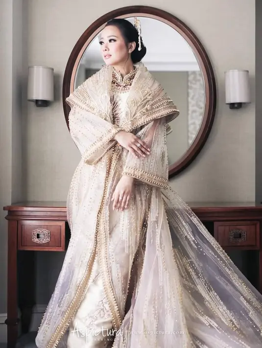 Yuanita Christiani tampil cantik dan berbeda mengenakan cheongsam. Ia memilih cheongsam mewah dengan nuansa keemasan. Berbagai kristal dan bordiran emas di sepanjang cheongsam dan outer yang dikenakannya terlihat menawan berpadu dengan kulit putih dan berbagai aksesori, sekaligus tatanan rambut dan makeupnya. Foto: Instagram.