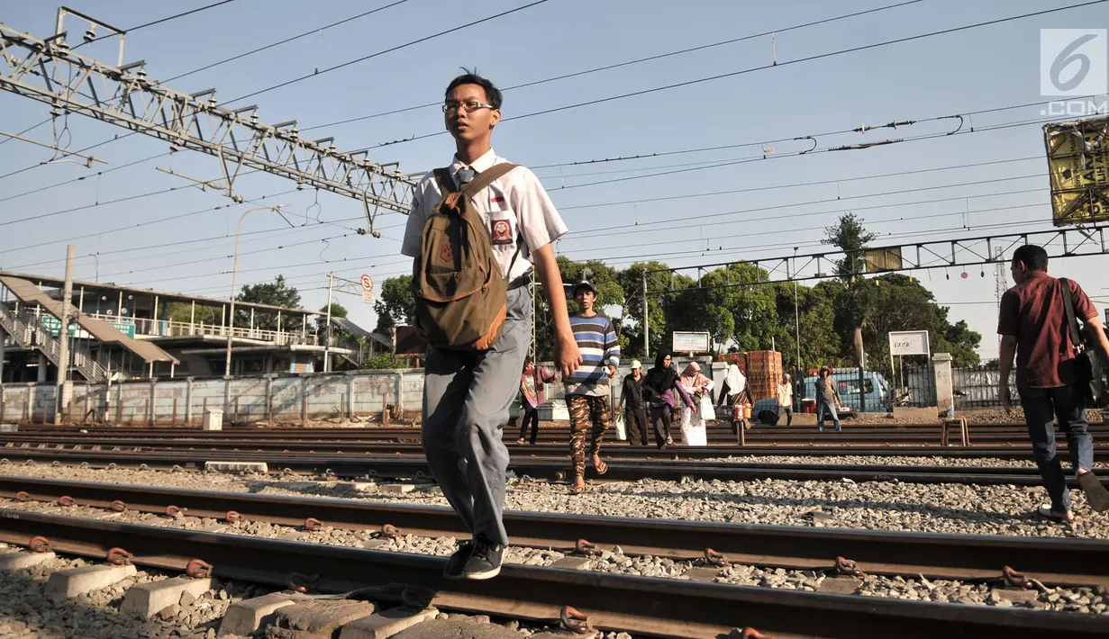 Seorang siswa menyeberangi perlintasan rel kereta api di kawasan Pisangan Baru, Jakarta, Selasa (10/9/2019). Mereka nekat menantang maut menyeberangi rel di dekat stasiun Jatinegara tersebut lantaran tidak adanya akses jembatan penyeberangan orang (JPO). (merdeka.com/Iqbal Nugroho)