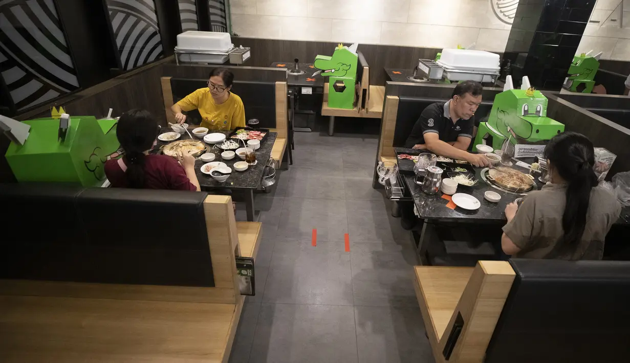 Pelanggan duduk bersebelahan dengan boneka kartun naga yang digunakan restoran untuk menjaga jarak fisik di Bangkok, Thailand, Senin (18/5/2020). Pemerintah Thailand mengizinkan pusat perbelanjaan dan bisnis kembali dibuka setelah sebelumnya ditutup karena pandemi COVID-19. (AP Photo/Sakchai Lalit)