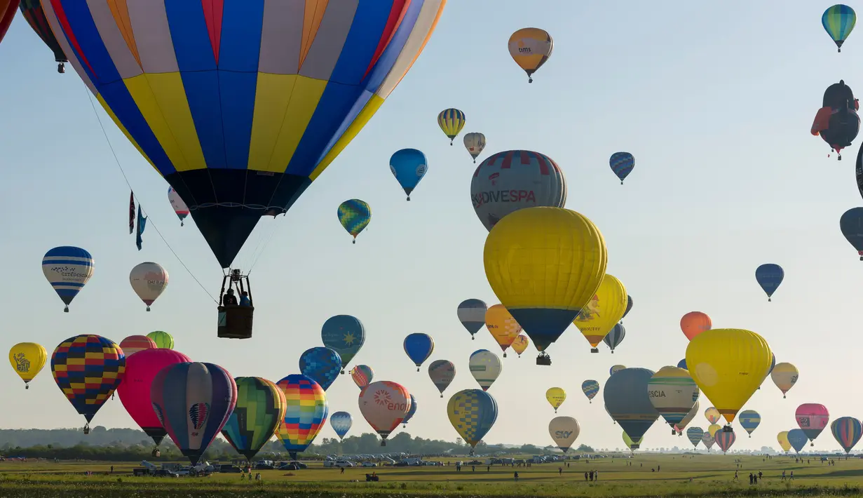 Ratusan balon udara terbang di pangkalan udara Chambley-Bussieres, Hagéville, Prancis, Senin (29/7/2019). Acara itu disebut sebagai salah satu festival balon udara terbesar di dunia. (Jean-Christophe VERHAEGEN/AFP)