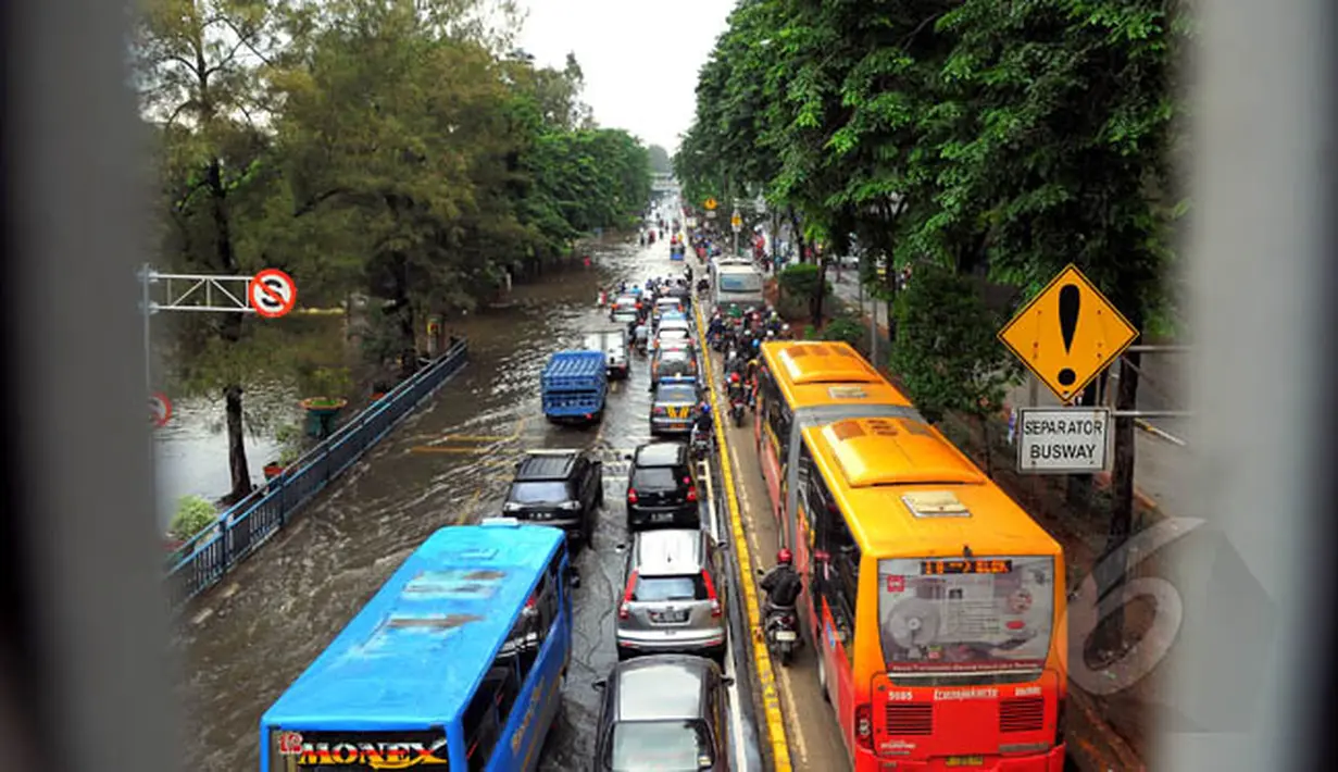 Sejumlah kendaraan melintasi genangan air di kawasan Grogol, Jakarta, Rabu (11/2). Hingga kini sejumlah kawasan di Jakarta masih tergenang banjir akibat dari hujan dengan intensitas tinggi yang mengguyur pada Minggu (8/2). (Liputan6.com/Faisal R Syam)