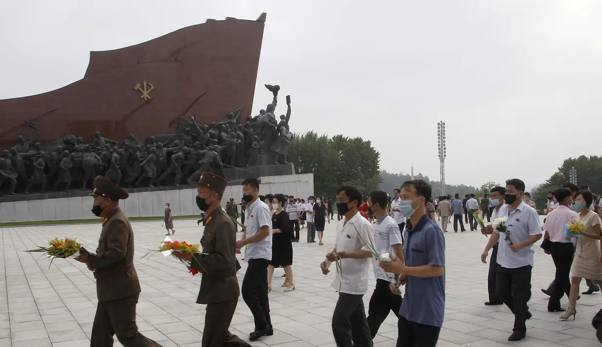 Sejumlah warga membawa bunga saat mengunjungi Mansu Hill untuk memberi penghormatan terhadap patung-patung perunggu dari Kim Il-sung dan Kim Jong-il pada peringatan 26 tahun kematian Kim Il-sung di Pyongyang, Korea Utara, Rabu (8/7/2020). (AP Photo/Jon Chol Jin)