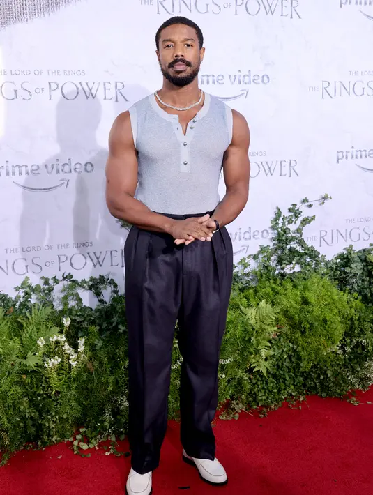 Michael B. Jordan tersenyum saat menghadiri pemutaran perdana "The Lord of the Rings: The Rings of Power" di The Culver Studios di Culver City, California (15/8/2022). Ia melengkapi penampilannya dengan kalung rantai perak dan sepatu pantofel putih. (Matt Winkelmeyer/Getty Images/AFP)