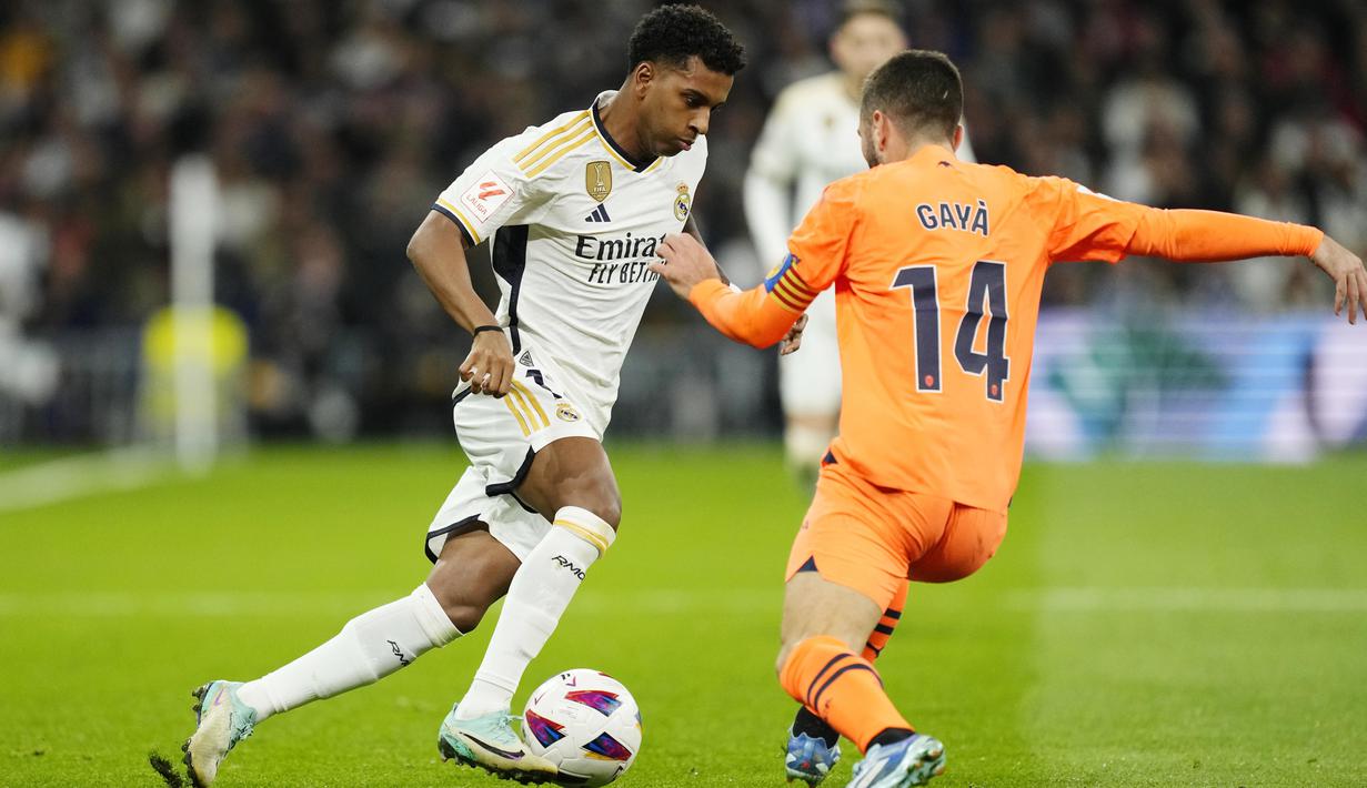 Pemain Real Madrid, Rodrygo berusaha melewati pemain Valencia, Jose Gaya, pada laga Liga Spanyol di Stadion Santiago Bernabeu, Sabtu (11/11/2023). Real Madrid berhasil unggul di laga ini berkat gol Dani Carvajal dan sepasang gol masing-masing dari Vinicius Junior dan Rodrygo. Sementara Valencia mampu memperkecil kedudukan berkat gol Hugo Duro. (AFP/Thomas Coex)