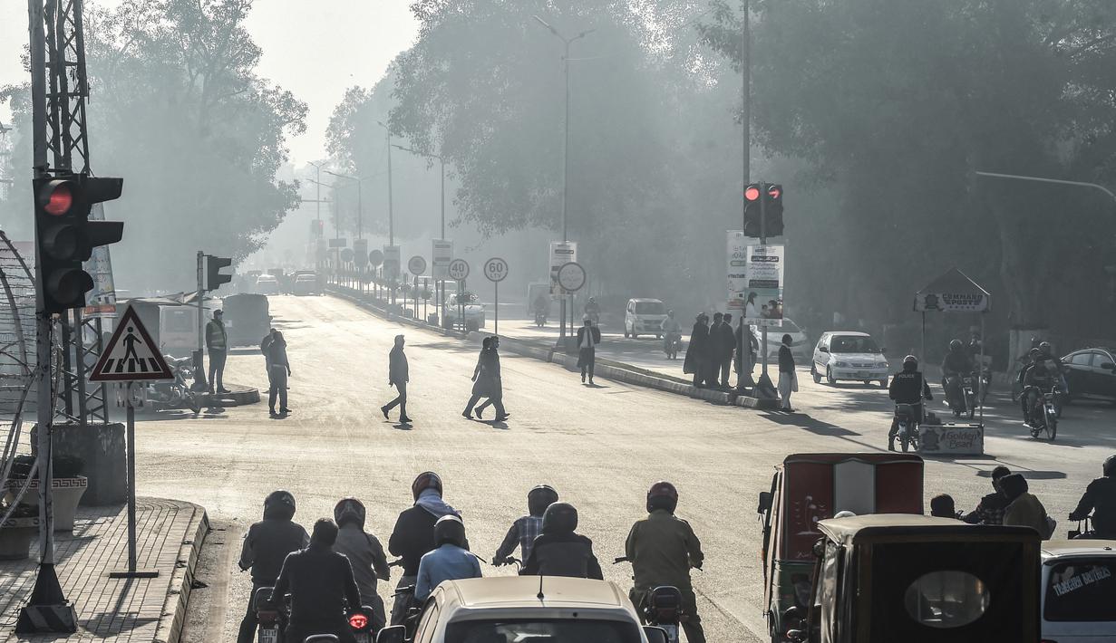 Orang-orang menyeberang jalan di tengah kondisi kabut asap di Lahore, Pakistan (23/11/2021). Kondisi kabut asap yang memburuk membuat Lembaga pendidikan, kantor swasta tutup selama tiga hari seminggu di Lahore. (AFP/Arif Ali)