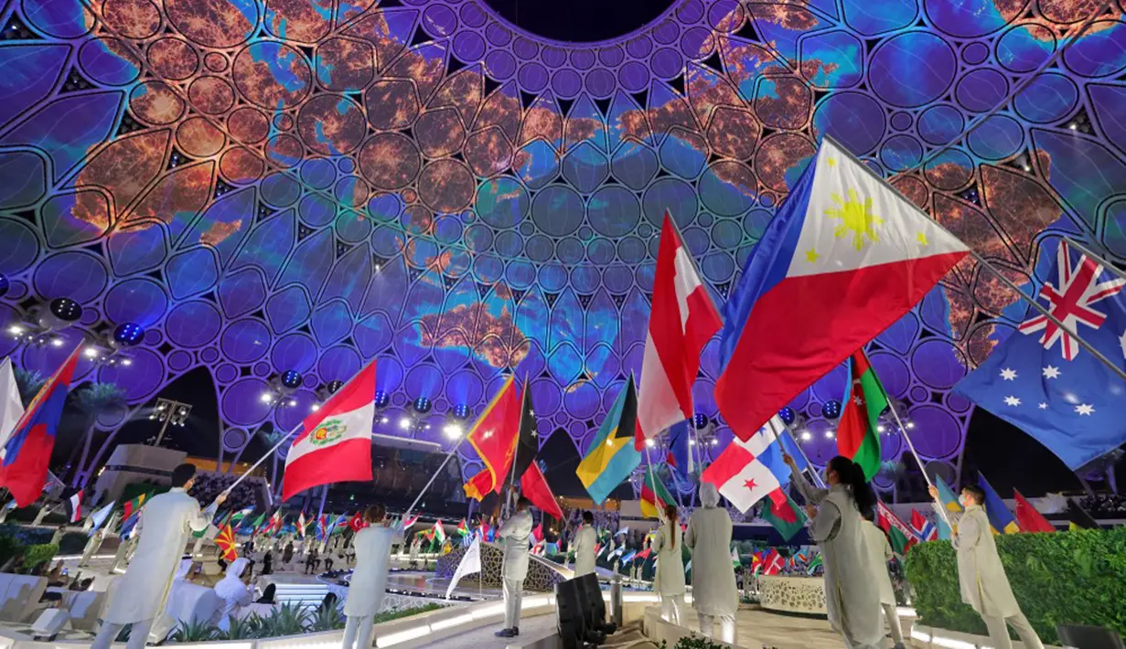 Para pembawa bendera untuk negara-negara peserta masuk selama upacara pembukaan Dubai Expo 2020 di Dubai, Uni Emirat Arab, 30 September 2021. Pembukaan Dubai Expo 2020 berlangsung mewah dengan menampilkan kembang api dan pertunjukan lampu untuk merayu dunia meski pandemi. (GIUSEPPE CACACE/AFP)