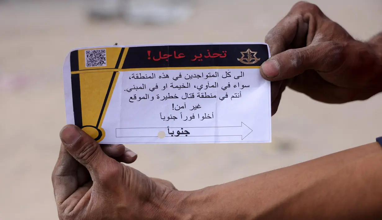 Seorang pria Palestina memegang selebaran yang dibagikan oleh tentara Israel pada 22 Mei 2025. (BASHAR TALEB/AFP)
