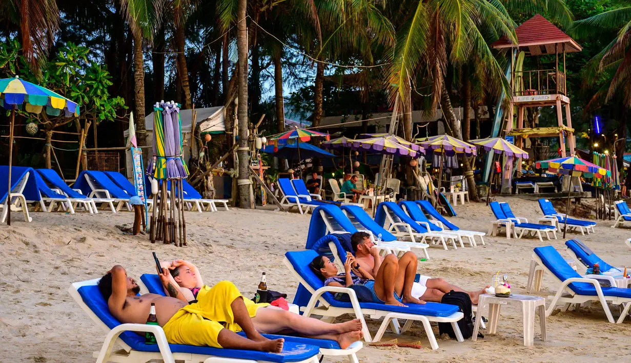 <p>Orang-orang bersantai saat para turis memanfaatkan program "Kotak Pasir Phuket" untuk pengunjung yang divaksinasi penuh terhadap virus corona Covid-19 di pulau Phuket Thailand (25/10/2021). (AFP/Mladen Antonov)</p>