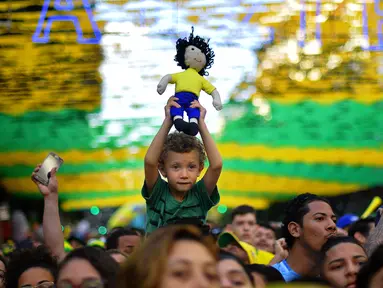 Seorang bocah yang menjadi fans timnas Brasil menyaksikan pertandingan  Grup E Piala Dunia 2018 melawan Swiss dari layar besar di Alzirao, Rio de Janeiro, 17 Juni 2018. (AFP PHOTO / CARL DE SOUZA)