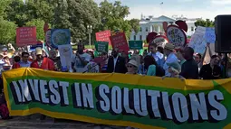 Demonstran membawa spanduk saat aksi di dekat Gedung Putih di Washington, AS, Kamis (1/6). Demonstran memprotes keputusan Donald Trump yang menarik AS dari perjanjian Paris tentang perubahan iklim yang disepakati pada 2015. (AP/ Susan Walsh)