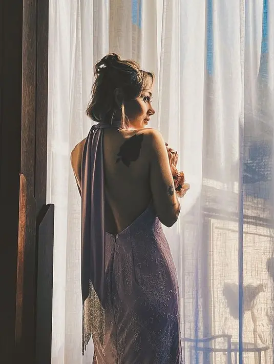 Dengan gaun bernuansa ungu, potongan halter neck dan bacless sukses mengekspos tato di punggungnya. [Foto: @sarawijayanto]
