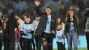 Pemain Uruguay, Luis Suarez (tengah) bersama ketiga anaknya melambaikan tangan kepada para penonton saat acara perpisahannya dengan Timnas Uruguay sebelum laga kualifikasi Piala Dunia 2026 melawan Paraguay yang berlangsung di Stadion Centenario, Montevideo, Uruguay, Sabtu (07/09/2024) WIB. (AFP/Dante Fernandez)