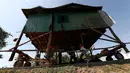 Penduduk desa Kamboja memindahkan sebuah rumah kayu di desa Pon Sang di sisi utara Phnom Penh, Kamboja (26/4/2020). Ini adalah cara bergerak tradisional yang dikumpulkan penduduk desa untuk saling membantu dengan menggunakan traktor dan batang kayu. dengan menjaga rumah tetap utuh. (AP/Heng Sinith)