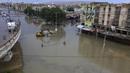 Orang-orang melintasi daerah banjir setelah hujan deras di Karachi, Pakistan, Minggu, (26/7/2020). Banjir melumpuhkan arus lalu lintas salah satu ruas jalan di Karachi. (AP Photo/Fareed Khan)