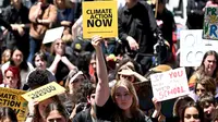 Para siswa sekolah memegang plakat saat mereka berbaris dalam unjuk rasa School Strike for Climate yang menyerukan aksi iklim di Melbourne pada 17 November 2023. (William WEST/AFP)