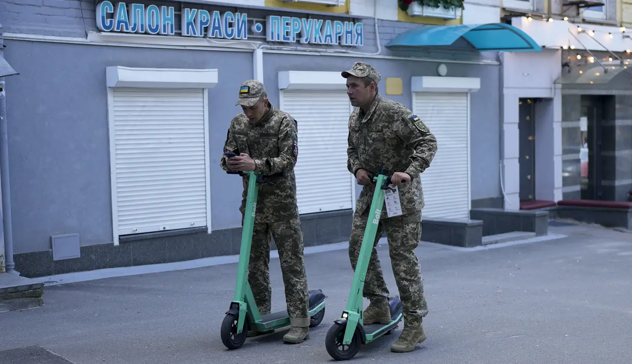 Dua tentara mengendarai skuter selama perayaan Hari Kyiv di Kyiv, Ukraina, Minggu (29/5/2022). Ibu kota Ukraina merayakan ulang tahun pendiriannya setiap Minggu terakhir bulan Mei. Kiev merayakan peringatan 1540 tahun pendiriannya, di mana tahun ini dirayakan di bawah darurat militer. (AP Photo/Natacha Pisarenko)