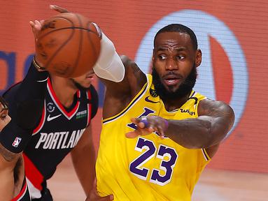 Pebasket Los Angeles Lakers, LeBron James, berebut bola dengan pebasket Portland Trailblazers,  Gary Trent Jr, pada babak pertama playoff NBA 2020 di AdventHealth Arena, Rabu (19/8/2020). LA Lakers takluk 93-100 atas Portland Trailblazers. (AFP/Mike Ehrmann/Getty Images)