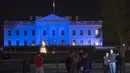 Pengunjung berkumpul di depan Gedung putih yang dihiasi cahaya warna biru untuk menandai Hari Kesadaran Autisme Sedunia, di Washington, DC, Minggu (2/4). Tanggal 2 April diperingati sebagai Hari Kesadaran Autisme Sedunia. (SAUL LOEB/AFP)