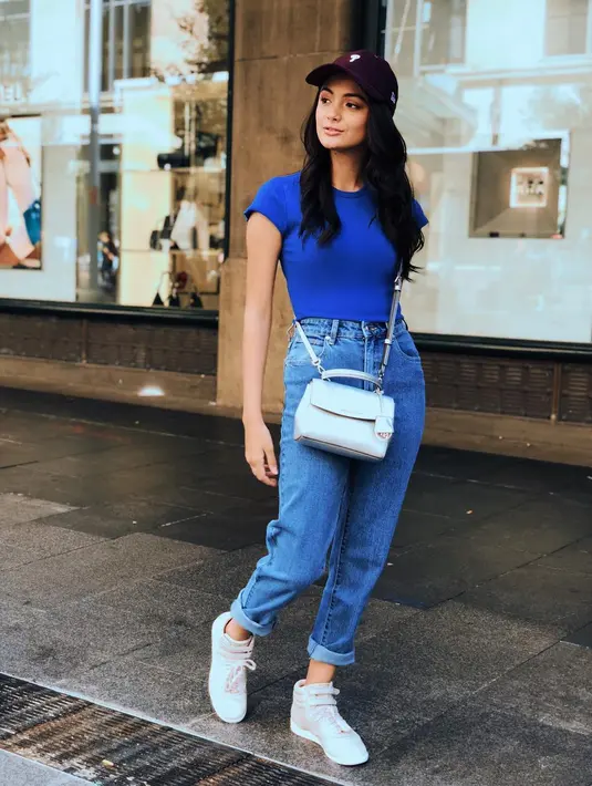 Di kesehariannya, Amanda memang tampak sering  mengenakan busana kasual. Dan kali ini ia memilih nuansa biru. Mulai dari celana jeans, kaus dan slig bagnya. Gayanya tampak sporty dengan sneakers dan topi hitamnya. (Instagram/amandarawles)