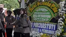 Polisi berdiri dekat karangan bunga ucapan bela sungkawa wafatnya Ani Yudhoyono menghiasi kawasan Puri Cikeas, Bogor, Jawa Barat, Minggu (2/6/2019). Istri Presiden ke-6 RI Susilo Bambang Yudhoyono (SBY) itu rencananya akan dimakamkan di TMP Kalibata pada siang ini. (Liputan6.com/Immanuel Antonius)