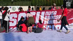 Sejumlah warga memberikan tanda tangan di spanduk saat aksi Satu Indonesia di area CFD, Bundaran HI, Minggu (30/7). Aksi ini digelar dalam rangka menyambut Raimuna Nasional XI Gerakan Pramuka. (Liputan6.com/Helmi Afandi)
