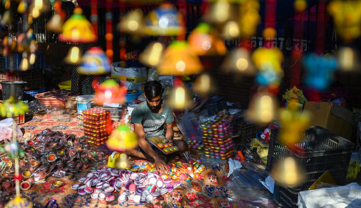 Seorang pembuat tembikar menjual lampu tanah jelang Festival Diwali di sepanjang pinggir jalan di New Delhi, India, 18 Oktober 2022. Festival Diwali atau dalam agama Hindu berarti Festival Cahaya melambangkan kemenangan baik atas keburukan, dan lampu atau pelita dinyalakan sebagai tanda perayaan serta harapan umat manusia. (Sajjad HUSSAIN/AFP)