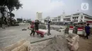 Pekerja menyelesaikan proyek revitalisasi di depan Stasiun Jakarta Kota, kawasan Kota Tua, Jakarta, Sabtu (23/7/2022). Pemprov DKI Jakarta menyatakan program revitalisasi di kawasan Kota Tua salah satunya bertujuan untuk meningkatkan aksesibilitas dengan mengintegrasikan beragam moda transportasi seperti kereta api, MRT, Transjakarta hingga angkutan perkotaan. (Liputan6.com/Faizal Fanani)