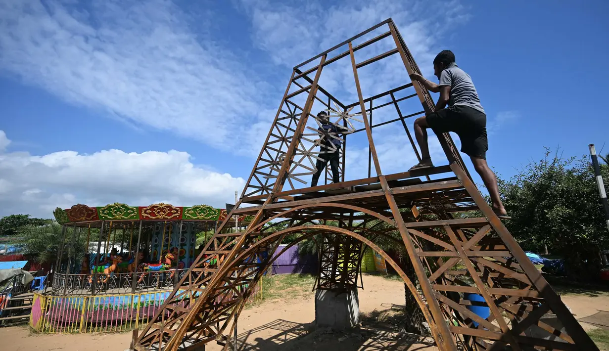 Para pekerja membangun model replika Menara Eiffel di sebuah taman di Puducherry, sebuah wilayah bekas koloni Prancis di India pada tanggal 18 Januari 2024. (Arun SANKAR/AFP)