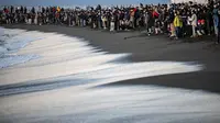 Orang-orang berkumpul di Pantai Selatan Chigasaki untuk menyaksikan matahari terbit pada Hari Tahun Baru di Prefektur Kanagawa, barat daya Tokyo (1/1/2021). (AFP/Philip Fong)