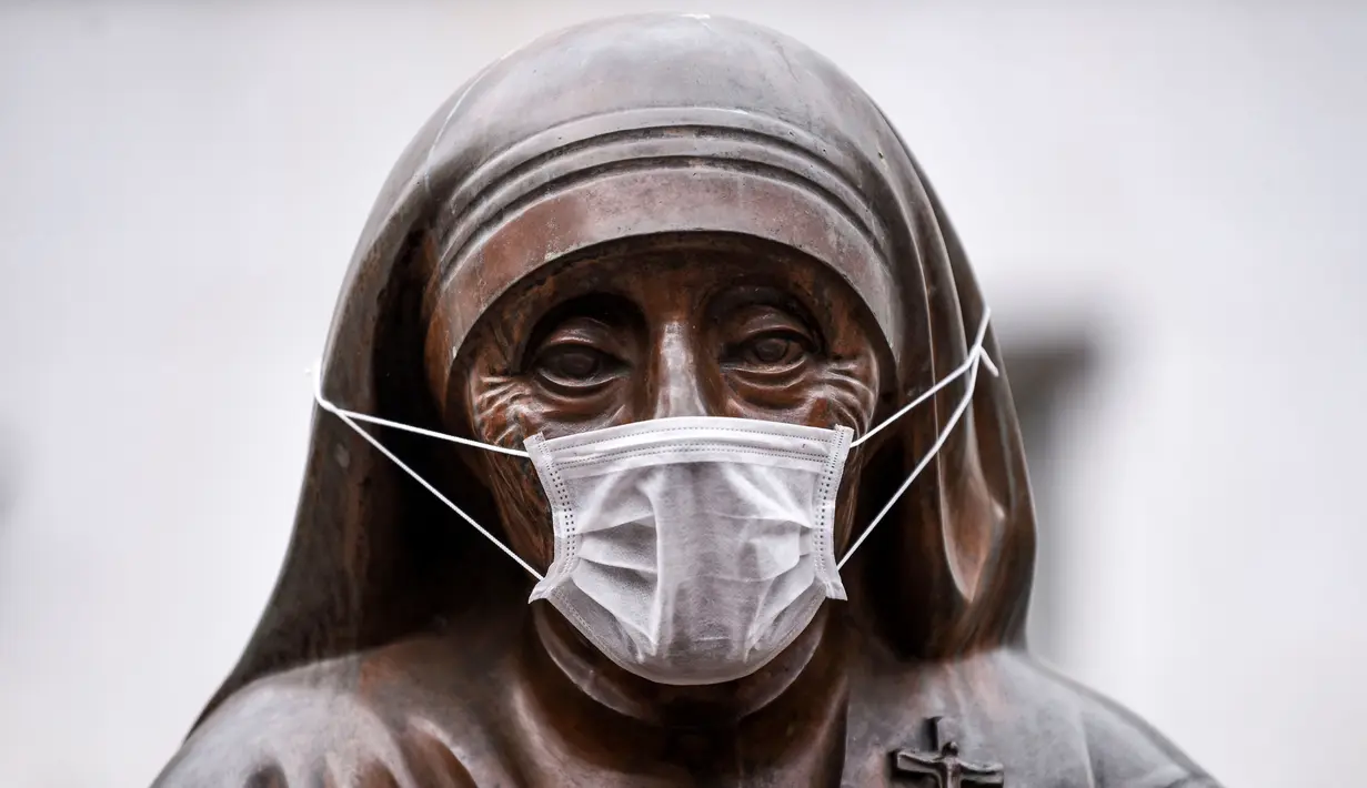 Masker terpasang pada wajah patung Bunda Teresa di Pristina, Kosovo, Kamis (19/12/2019). Pristina dan beberapa kota di Kosovo mengalami polusi udara tingkat tinggi. (Armend NIMANI/AFP)