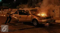 Pemilik mobil berusaha menyelamatkan barang miliknya saat mobil terbakar di jalan layang Latuharhari, Jakarta, Kamis (18/9/2015). Diduga kebakaran akibat konsleting listrik yang terjadi dibagian depan kap mobil. (Liputan6.com/Faizal Fanani)