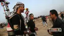 Pemuda Palestina, Mohammad Safy (kiri) saat membagikan jus kepada pengunjuk rasa di perbatasan Israel dengan Gaza, Jumat (13/4). Sebanyak 33 warga Palestina tewas dalam unjuk rasa tersebut. (MAHMUD HAMS/AFP)