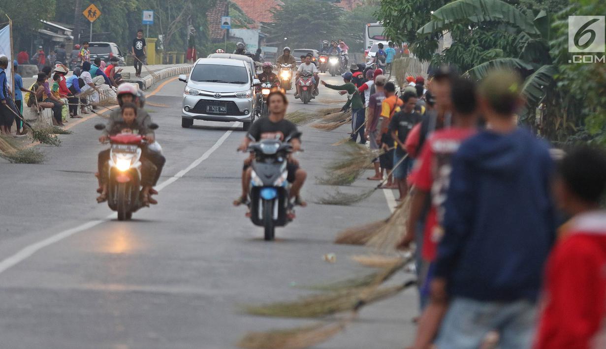 Warga membawa sapu menunggu pengguna jalan memberi sedekah dengan melempar uang di Jembatan Sewo, Jalur Pantura Sukra Indramayu, Jawa Barat, Senin (3/6/2019). Kehadiran pencari sedekah tersebut biasanya kian bertambah banyak saat menjelang arus mudik Lebaran. (Liputan6.com/Herman Zakharia)