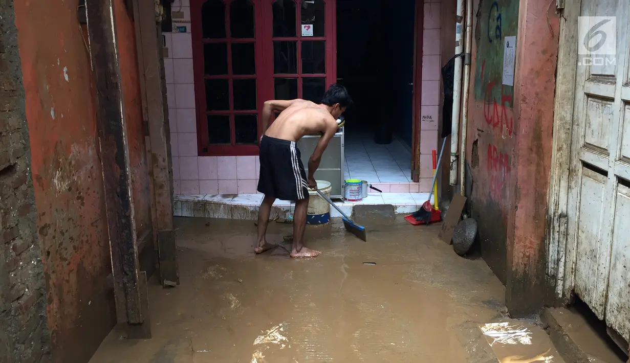 Seorang warga membersihkan lumpur sisa banjir yang menggenangi rumahnya di kawasan Rawajati, Jakarta Selatan, Selasa (6/2). Banjir yang mulai surut dimanfaatkan warga untuk membersihkan lumpur. (Liputan6.com/Immanuel Antonius)