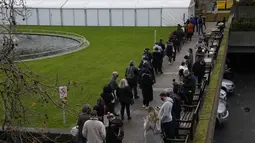 Orang-orang antre untuk suntikan vaksin booster Covid-19 di Rumah Sakit St Thomas, London, Senin (13/12/2021). Antrean panjang terbentuk di pusat vaksinasi di Inggris ketika pemerintah mendorong agar semua orang dewasa mendapatkan vaksin booster untuk cegah penyebaran Omicron. (AP Photo/Matt Dunham)