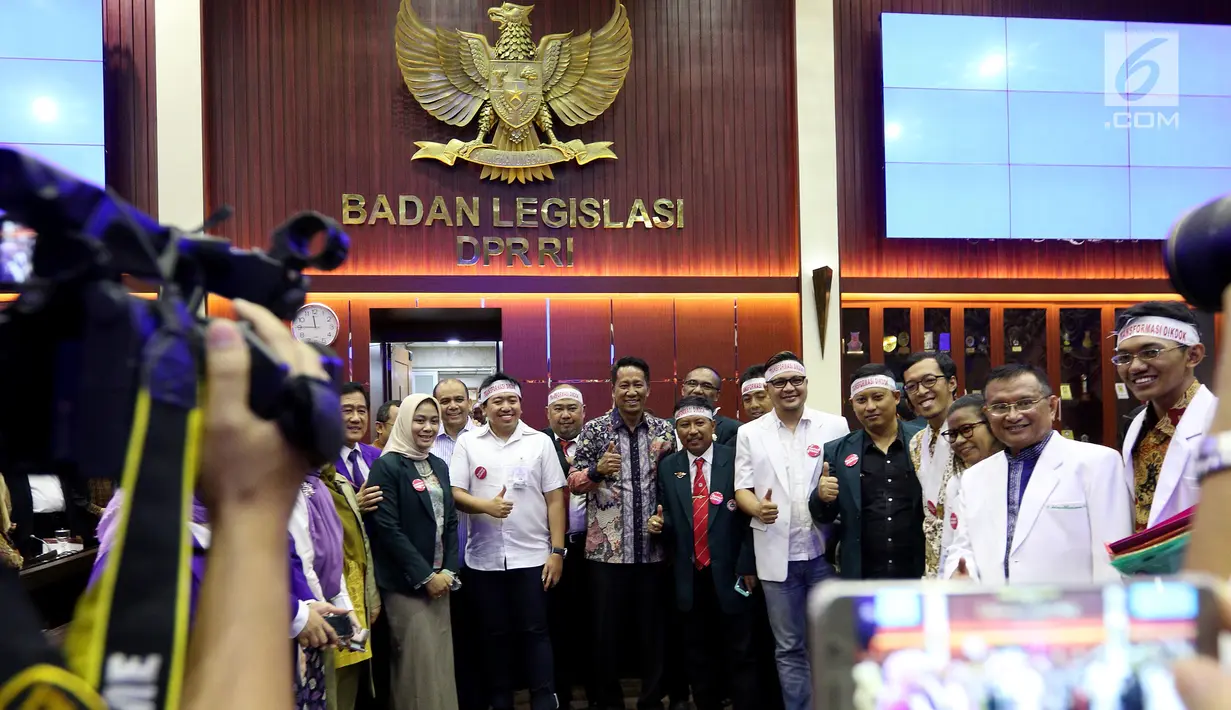 Anggota IDI mengenakan ikat kepala berfoto bersama Ketua Baleg DPR Supratman Andi Agtas  mengikuti Rapat Dengar Pendapat Umum (RDPU) dengan Badan Legislasi DPR di Kompleks Parlemen, Jakarta, Senin (2/4). (Liputan6.com/JohanTallo)