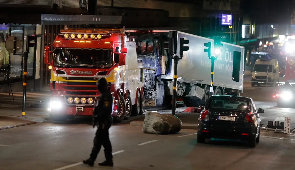 Petugas keamanan setempat berjaga di dekat truk yang menabrak kerumunan orang di Jalan Drottninggatan, pusat kota Stockholm, Swedia (8/4). (AP Photo / Markus Schreiber)