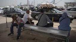 Penumpang duduk di bangku saat mereka menunggu untuk menaiki feri menuju Tangier di pelabuhan Algeciras, Spanyol, Rabu (15/6/2022). Ribuan warga negara Maroko yang bekerja dan tinggal di Eropa melewati Selat Gibraltar saat mereka kembali untuk menghabiskan liburan musim panas di Maroko. (JORGE GUERRERO / AFP)