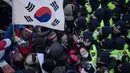 Demonstran anti-Korea Utara terlibat saling dorong dengan polisi saat melakukan aksi menyambut kedatangan kapal feri Korea Utara yang membawa rombongan seni yang akan tampil di Olimpiade Musim Dingin Pyeongchang 2018, Korea Selatan (6/2). (AFP/Ed Jones)