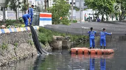 Petugas melepas kain waring atau jaring yang menutupi Kali Item di Kemayoran Jakarta, Rabu (14/11). Pelepasan waring yang sebagian dalam kondisi sudah robek itu dilakukan lantaran banyak warga yang membuang sampah di atasnya (Merdeka.com/Iqbal S. Nugroho)