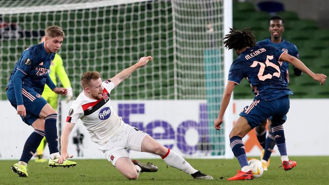 Bek Dundalk, Andy Boyle (kiri) bersaing dengan gelandang Arsenal, Mohamed Elneny pada pertandingan Grup B Liga Europa 2020/2021 di Stadion Aviva, Jumat (11/12/2020) dini hari WIB. Arsenal menang 4-2 saat bertandang di markas wakil Irlandia, Dundalk. (Paul Faith / AFP)
