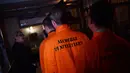 Para pengunjung mengenakan baju tahanan berwarna oranya saat memasuki bar koktail Alcotraz  di London , 11 Oktober 2018. Pengunjung harus mengganti pakaian mereka dengan baju tahanan untuk memasuki bar berkonsep penjara ini. (BEN STANSALL / AFP)