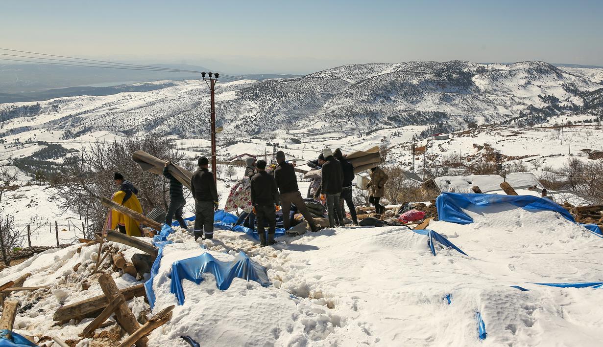 Penduduk desa berusaha mengeluarkan bahan alas tidur mereka dari rumah yang runtuh di desa Buyuknacar di Kahramanmaras, Turki, Rabu, 15 Februari 2023. Sementara jumlah korban tewas hampir pasti akan meningkat lebih jauh lagi, banyak dari puluhan ribu korban selamat yang kehilangan tempat tinggal masih berjuang untuk memenuhi kebutuhan dasar, seperti mencari perlindungan dari hawa dingin yang menggigit. (AP Photo/Emrah Gurel)