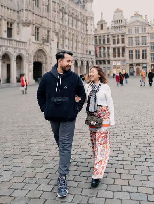 Keduanya tampil dengan outfit bernuansa yang lebih santai. Kiky tampil mengenakan atasan sweater putih dipadu dengan celana kain bermotif, sedangkan suaminya mengenakan hoodie berkantung di bagian depan berwarna biru navy, dipadu dengan jogger pants abu-abu. Foto: Instagram.