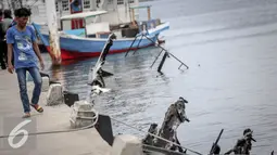 Warga melihat bangkai kapal Zahro yang terlihat hangus di pelabuhan Muara Angke, Jakarta, Selasa (3/1). Kondisi bangkai kapal yang terbakar pada Minggu (1/1) itu telah karam di sekitar dermaga Pelabuhan Kali Adem, Muara Angke. (Liputan6.com/Faizal Fanani)