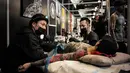 Seorang pria terbaring saat proses pembuatan tato di acara Paris Tattoo Convention di Grand Halle de la Villette, Paris, Prancis, Jumat (9/3). Paris Tattoo Convention berlangsung dari tanggal 9 sampai 11 Maret. (Philippe LOPEZ/AFP)
