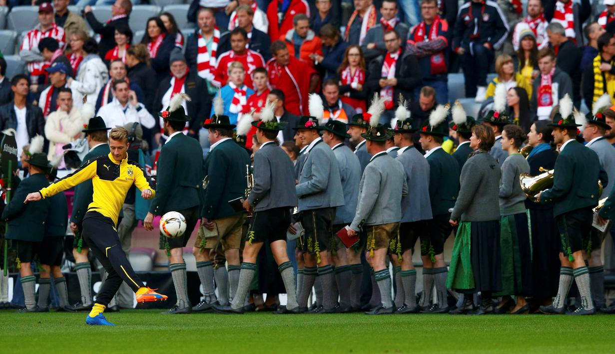 Pemain Borussia Dortmund Marco Reus melakukan pemanasan didekat  para pemusik Bavaria sebelum partai Bayern Munich dan Borussia Dortmund di Stadion Allianz Arena, Muenchen, Minggu (4/10/2015). (REUTERS/Michael Dalder)