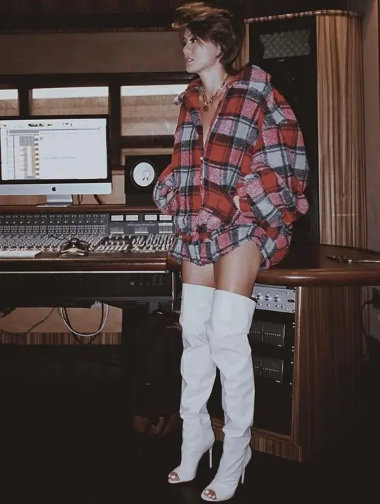 Simpel tapi stylish, Agnez Mo memadukan oversized plaid shirt dengan over the knee boots warna putih. (Instagram/agnezmo).